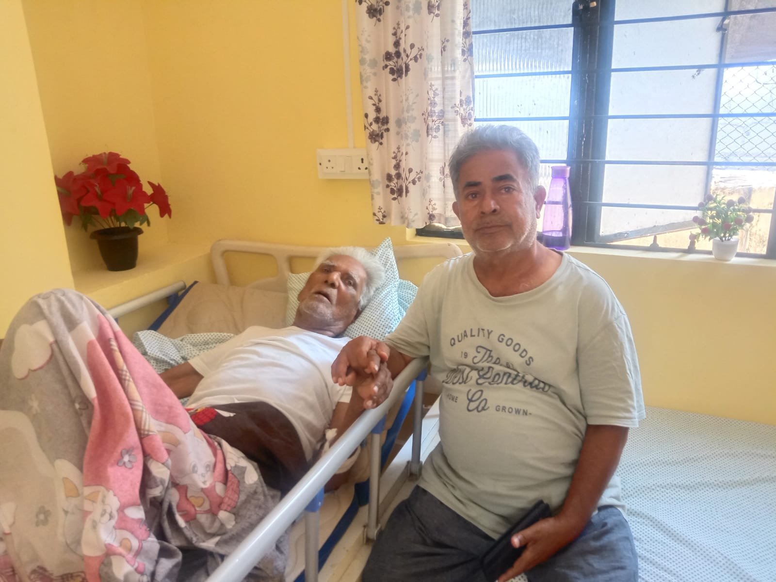 A caregiver holding the hand of an elderly resident at Sreekara Health Care Home